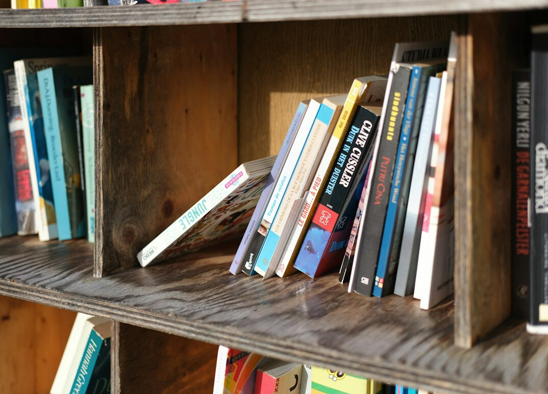 Rows of antique leather-bound books on wooden library shelves