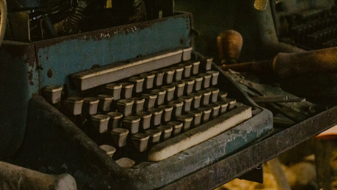 Hands of a writer typing on a vintage typewriter beside a notebook